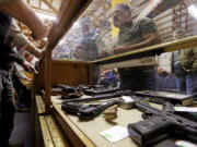 In this Oct. 20, 2017 photo, a case is filled with pistols before an auction of the guns at Johnny’s Auction House, where the company handles gun sales for several police departments and the Lewis County Sheriff’s Office, in Rochester, Wash. Law enforcement officials around the U.S. are split over the longtime practice among police departments of selling the guns they confiscate.