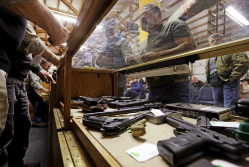 In this Oct. 20, 2017 photo, a case is filled with pistols before an auction of the guns at Johnny’s Auction House, where the company handles gun sales for several police departments and the Lewis County Sheriff’s Office, in Rochester, Wash. Law enforcement officials around the U.S. are split over the longtime practice among police departments of selling the guns they confiscate.