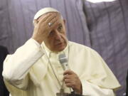 Pope Francis touches his forehead as he talks with journalists during his flight from Lima, Peru, to Rome on Sunday.