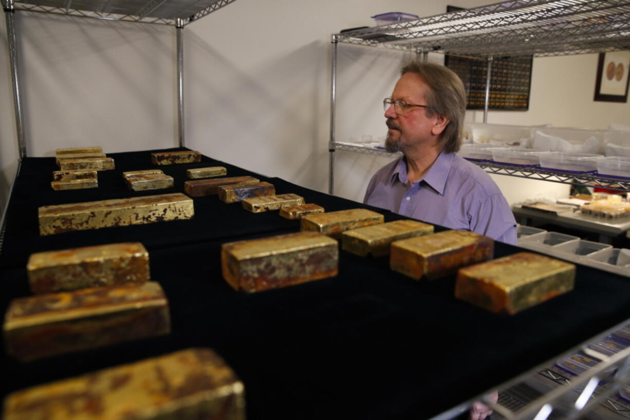 Chief scientist Bob Evans looks at gold bars recovered from the S.S. Central America steamship that went down in a hurricane in 1857 in a laboratory Tuesday in Santa Ana, Calif. More than $50 million worth of gold bars, coins and dust described as the greatest lost treasure in U.S. history is about to make its public debut in California. (AP Photo/Jae C.