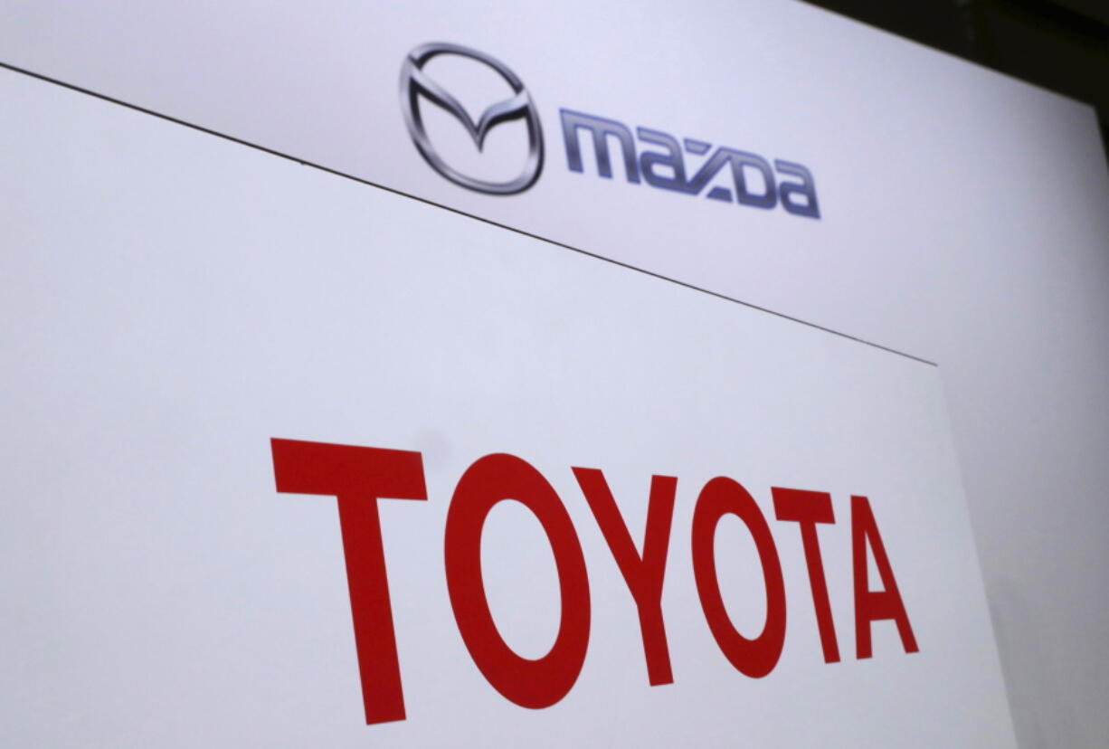 FILE- In this Aug. 4, 2017, file photo, logos of Toyota Motor Corp., bottom, and Mazda Motor Corp., top, are placed prior to a news conference in Tokyo. Japanese automakers Toyota and Mazda have picked Alabama as the site of a new $1.6 billion joint-venture auto manufacturing plant, a person briefed on the decision said Tuesday, Jan. 9, 2018.