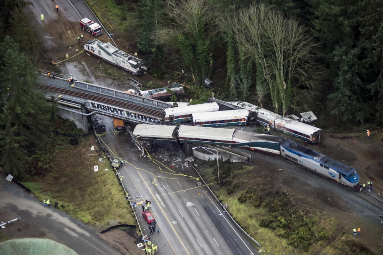 Cars from an Amtrak train that derailed lie spilled in DuPont on Dec. 18. A conductor who was injured when a speeding Amtrak train flew off the tracks and onto Interstate 5 last month filed a lawsuit Wednesday against the passenger rail company. Lawyers for Garrick Freeman of Bellevue say Amtrak failed to provide a safe work environment.