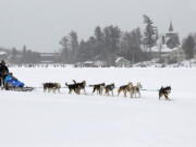 John Houghton, of Vermontville, N.Y., and his sled dog team, give a ride to a couple Jan. 30, 2015, in a snowfall, around Mirror Lake in Lake Placid, N.Y.