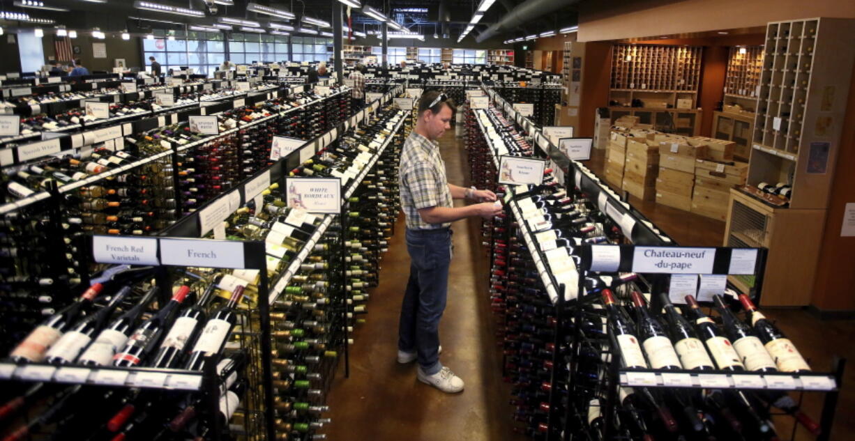 FILE- In this June 30, 2017, file photo, a worker at a state liquor store changes prices on wine, liquor and beer in Salt Lake City. In Mormon dominated Utah where alcohol is frowned upon, liquor sales keep climbing each year. The two-decade rise is likely fueled by a steady influx of new out-of-state residents drawn for jobs and a thriving tourism sector driven by snow-capped mountains and red-rock national parks.