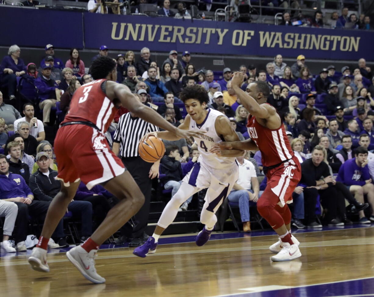 Washington guard Matisse Thybulle (4) drives between Washington State forward Robert Franks, left, and guard Milan Acquaah, right, Sunday, Jan. 28, 2018, in the first half of an NCAA college basketball game in Seattle. (AP Photo/Ted S.