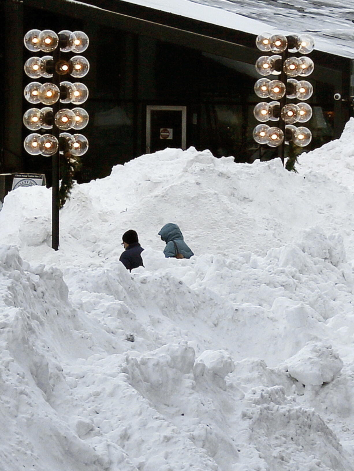 People walk between large piles of plowed snow outside Quincy Market on Friday in Boston. Frigid temperatures followed Thursday’s snowstorm on the East Coast.