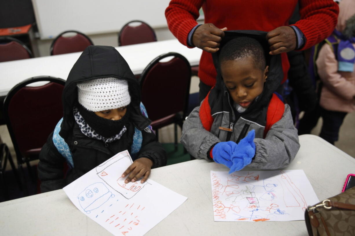 Teacher Loraine Wilson, top right, helps bundle up pre-kindergarten students as they wait to be picked up at the end of a school day at Lakewood Elementary School in Baltimore. The recent spell of cold weather exposed the poor state of school buildings in many big-city East Coast districts, including Baltimore. Lakewood students were sent back home Monday morning after pipes burst just as buses began dropping youngsters off. The school was able to reopen for classes Tuesday.