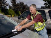 Scott Abels, a NOW volunteer, puts a notice on a car with an out-of-state license plate in the Landover-Sharmel neighborhood.