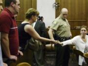 Heidi Fero, right, looks at her then-fiancé, Dustin Goodwin, partially visible at far left, as she hands her jewelry to her mother, Joan Fero, following sentencing on May 2, 2003.