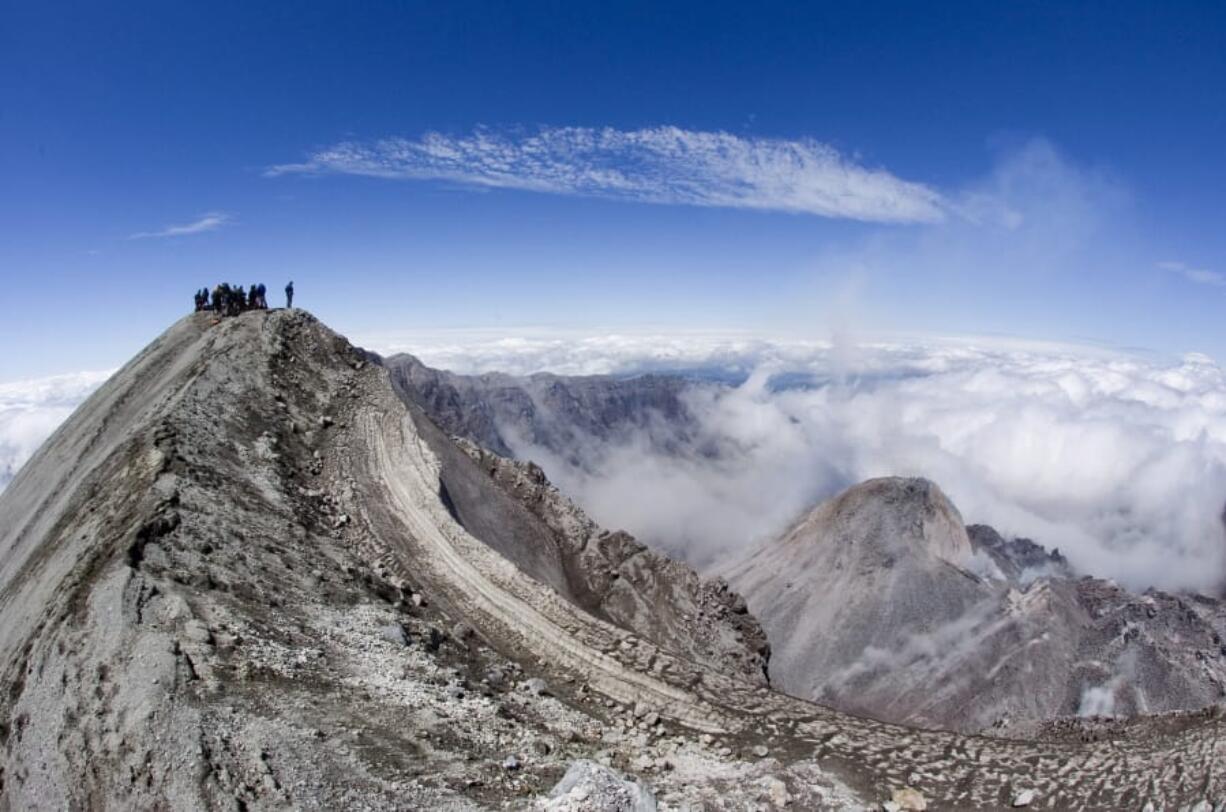 Members of the media stand at the 8,363-foot summit of Mount St. Helens in 2006 after officials announced the resumption of climbing on the volcano. The online system created for climbing permit sales crashed Thursday, frustrating thousands of hopeful climbers.