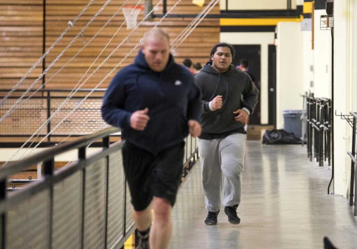 Angel Terry runs behind Hudson’s Bay assistant wrestling coach Dick Widle, left, as he prepares for Saturday’s 3A regional wrestling meet.