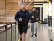 Angel Terry runs behind Hudson’s Bay assistant wrestling coach Dick Widle, left, as he prepares for Saturday’s 3A regional wrestling meet.