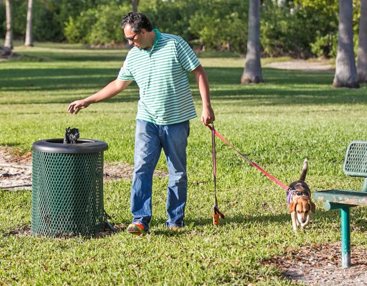 Emmanuel Cabrera Muoz properly disposes of his dog’s waste in a plastic bag and throws it in a trash can Feb. 7 at Kennedy Dog Park in Coconut Grove. C.M.