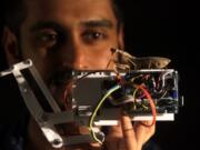 Lead author Vivek Nityananda holds a praying mantis atop a mantis-inspired robot arm.