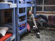 Robert Hardy takes off his shoes at his bed in the Winter Hospitality Overflow shelter at St. Paul Lutheran Church in Vancouver earlier this month. St. Paul Lutheran Church is one of two churches that have long hosted the WHO shelter in Clark County, providing men with a meal and safe place to sleep.