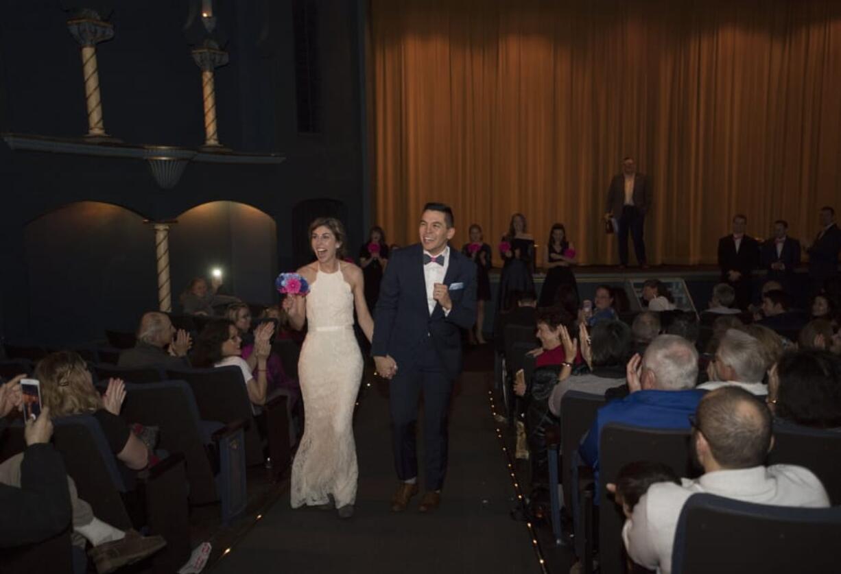 Tami Weidert and Nick Calais make their way up the aisle at Liberty Theatre in Camas after taking their wedding vows Friday afternoon. Wedding guests received movie popcorn before the ceremony, and a slideshow featuring the couple played on the big screen.