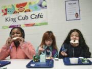 Fourth-graders Neveah Brown, left, and Sophie Whitworth eat bagels with third-grader, Andrea Vercher, during breakfast at Martin Luther King Elementary School in Vancouver. “When you’re doing the work every day with the kids you love, when kids are coming in hungry, we feed them,” Principal Janell Ephraim said.