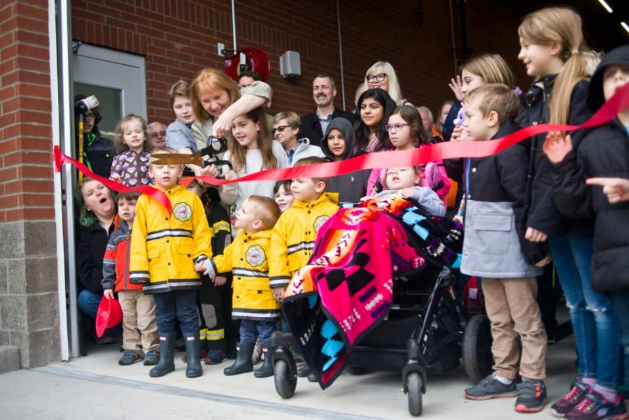 Vancouver Mayor Anne McEnerny-Ogle gets some help cutting the ribbon for Vancouver Fire Department’s Fire Station 2 on Saturday. Many attended the event, including young families and children who hoped to become firefighters.