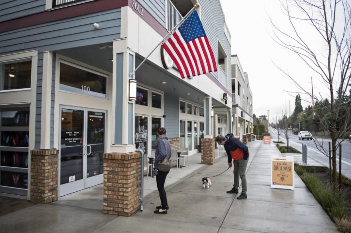 Gabby White, left, and Justin Lee, right, both of Vancouver, walk their new cocker spaniel puppy, Ripley, along the sidewalk next to Felida Village, which opened in 2015. The mixed-use development has retail space, apartments and a vacation rental. Developer Ron Edwards is now one of the people bringing a similar project to Ridgefield.