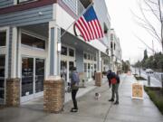 Gabby White, left, and Justin Lee, right, both of Vancouver, walk their new cocker spaniel puppy, Ripley, along the sidewalk next to Felida Village, which opened in 2015. The mixed-use development has retail space, apartments and a vacation rental. Developer Ron Edwards is now one of the people bringing a similar project to Ridgefield.