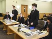 Cascadia Technical Academy students from left, Cameron Achziger, Justin Bates and David Guiher, listen as Camas High School freshman Hayden Devore, who acted as a lawyer for the defense, center, gives opening statements during a mock trial Thursday at the Clark County Courthouse.