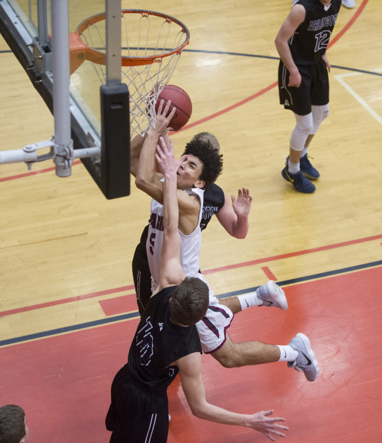 Prairie’s Zeke Dixson (5) makes a shot through Arlington’s Anthony Whitis (10) and Joseph Schmidt (24) during the 3A regional boys basketball game at Battle Ground High School, Saturday February 24, 2018.