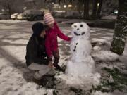 Martin Bizjack of Vancouver and his daughter, Ellen, 7, put the finishing touches on their snowman in Southeast Vancouver while playing in the winter weather Tuesday night.