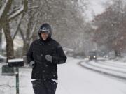 Doug Gillespie of Vancouver takes the winter weather in stride as he jogs through Cascade Park on Tuesday morning. Gillespie said he didn't mind running in the snow. "At least it's better than rain," he said.