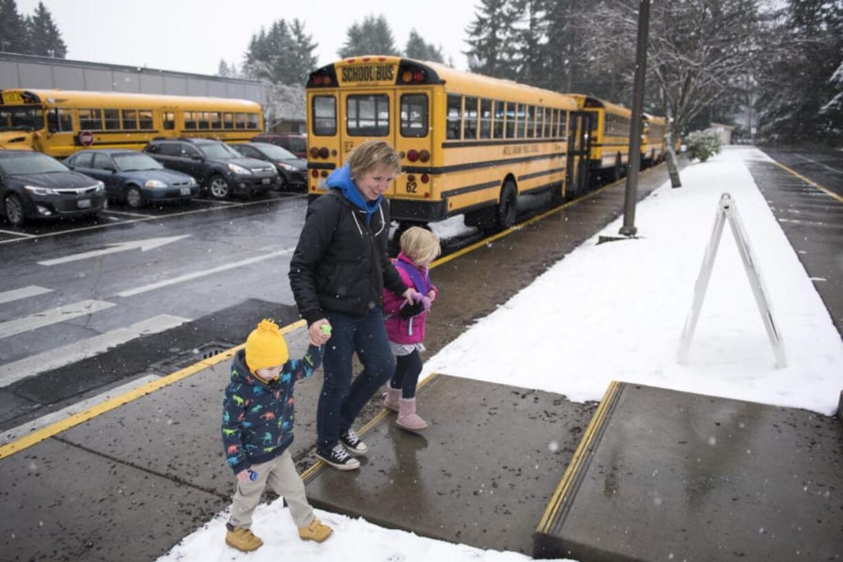 Sarah Reese, center, and her children Max, 3, left, and Madison, 5, right, head to their car after Reese picked up Madison after students were released early from Pleasant Valley Primary School north of Vancouver. The National Weather Service announced a winter storm warning at 8:30 a.m., prompting schools to announce early closures and canceled activities.