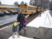 Sarah Reese, center, and her children Max, 3, left, and Madison, 5, right, head to their car after picking up Madison for early release on Tuesday morning at Pleasant Valley Primary School in Vancouver. The school let out early because of heavy snowfall predicted throughout the day.