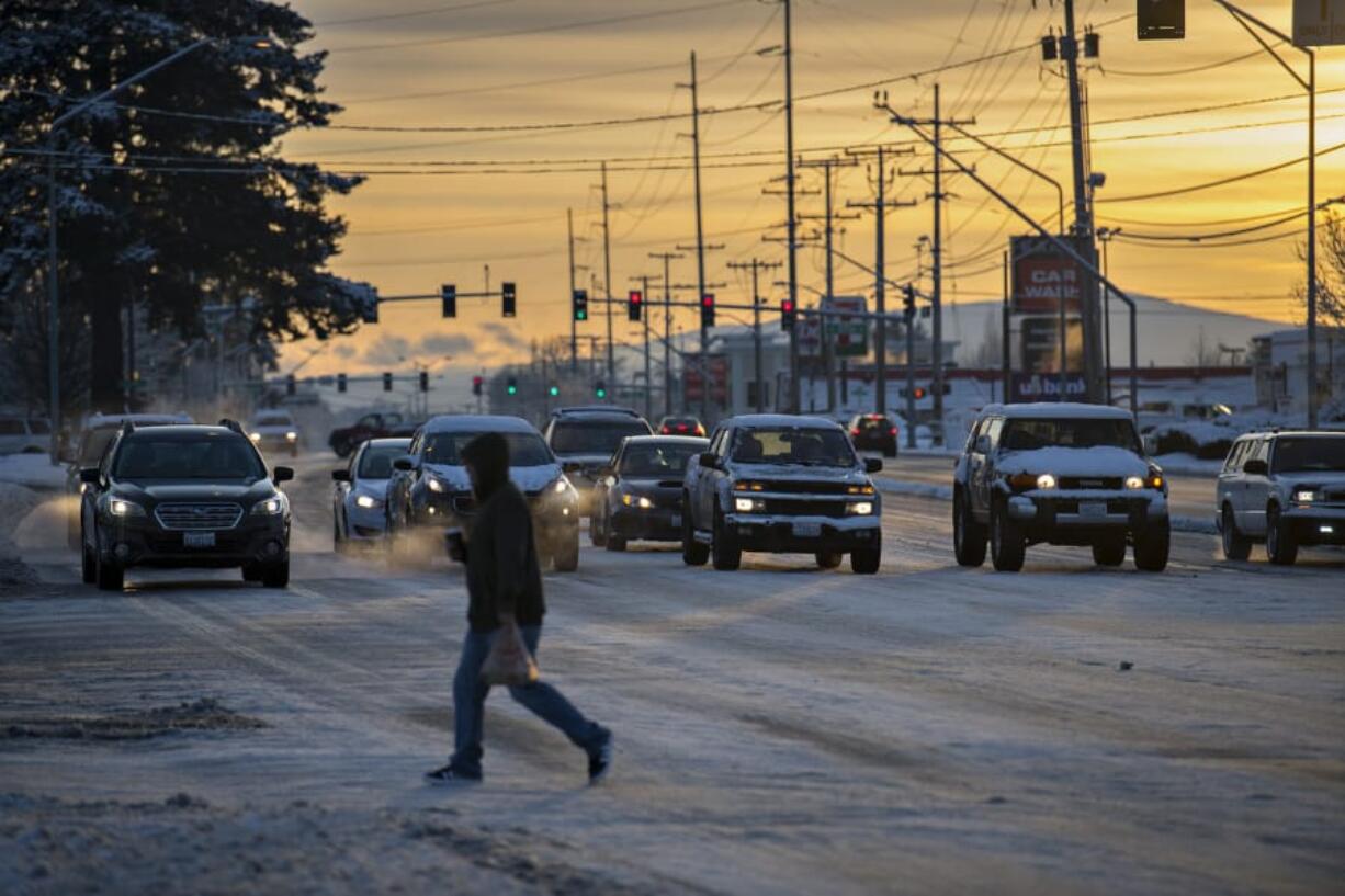 The sun rises over a frosty Southeast Mill Plain Boulevard as motorists and pedestrians navigate the intersection near Chkalov Drive on Wednesday morning.