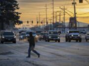 The sun rises over a frosty Southeast Mill Plain Boulevard as motorists and pedestrians navigate the intersection near Chkalov Drive on Wednesday morning.