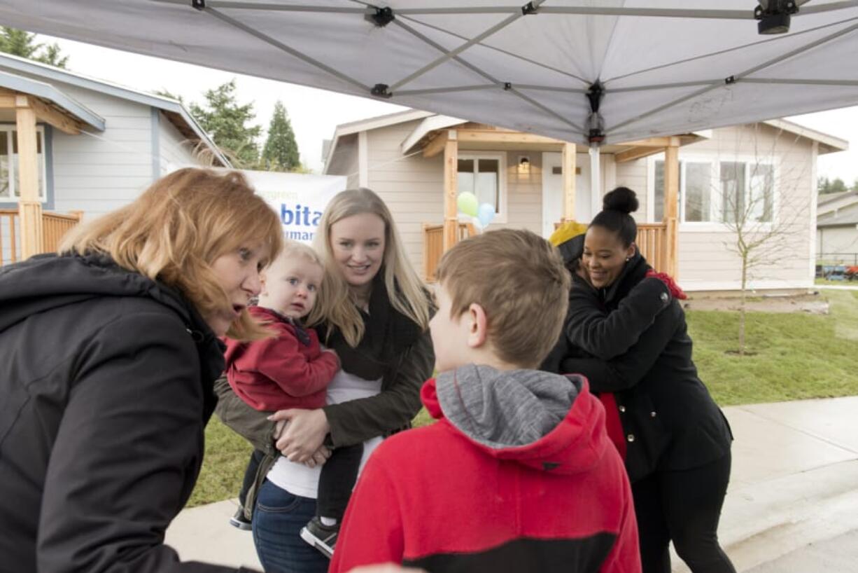 Vancouver Mayor Anne McEnerny-Ogle speaks with Taylor Hauxhurst, 12, about his new home, while his mother, Tiffany Hauxhurst, and brother Grayson, 2, look on. Dakota Palmore, who also got the keys to her Habitat for Humanity home on Sunday, is greeting a well-wisher after the ceremony commemorating the two families’ new homes.