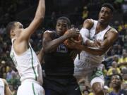 Oregon's Paul White, left, watches as temmate Kenny Wooten, right, works against Washington's Noah Dickerson for a rebound during the first half of an NCAA college basketball game Thursday, Feb. 8, 2018, in Eugene, Ore.