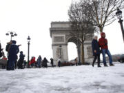 Tourists stroll on the snow-covered Champs Elysees avenue near the Arc de Triomphe in Paris, France, Friday, Feb. 9, 2018. The Eiffel Tower is closed and authorities are telling drivers in the Paris region to stay home as snow and freezing rain have hit a swath of France ill-prepared for the wintry weather.