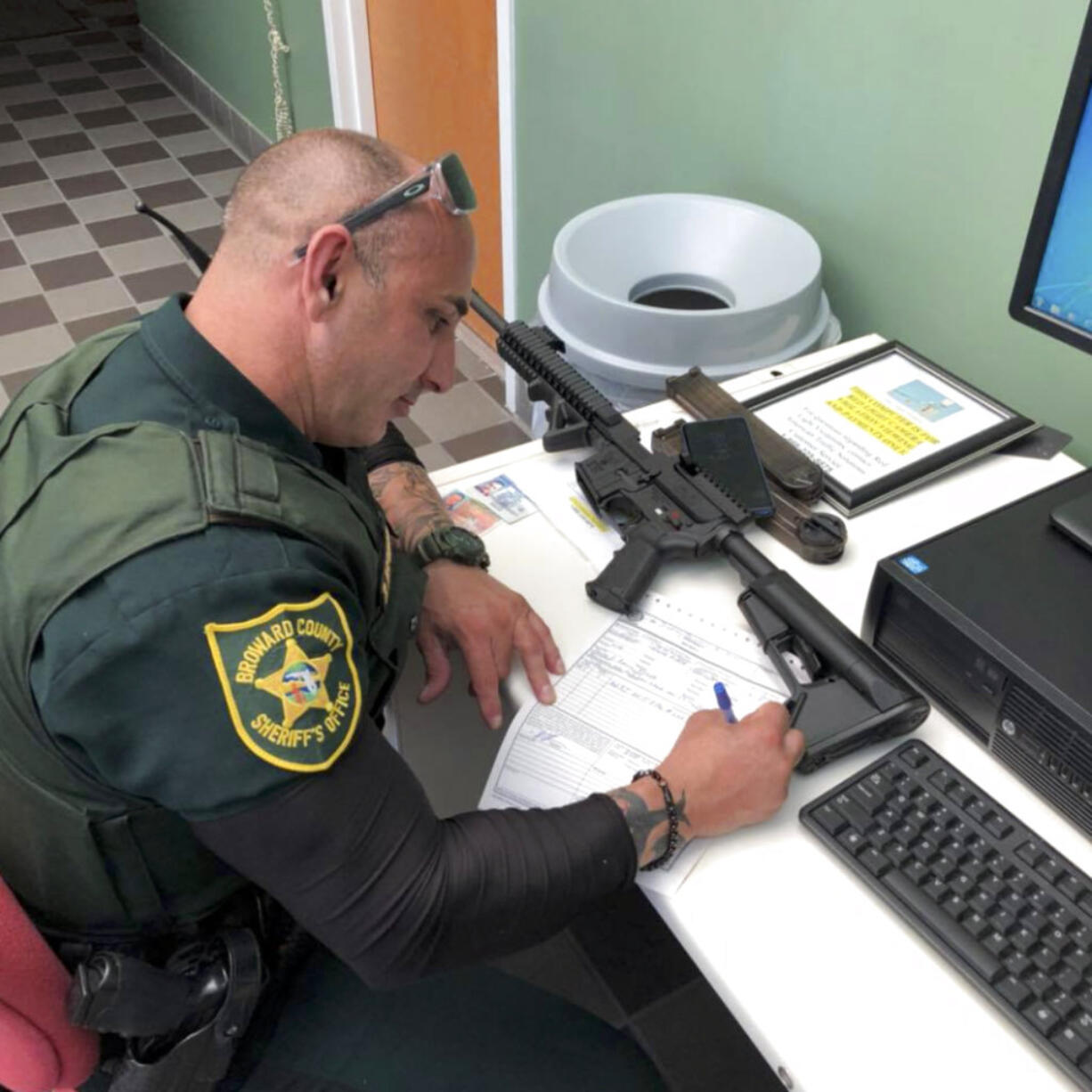 In this Feb. 16, 2018, photo provided by Ben Dickmann, a deputy at the Broward County sheriff's office in Ft. Lauderdale, Fla., processes paperwork to take possession of and destroy Dickmann's AR-style firearm. Dickmann decided to turn in his weapon after the shooting at Marjory Stoneman Douglas High School in nearby Parkland, Fla.