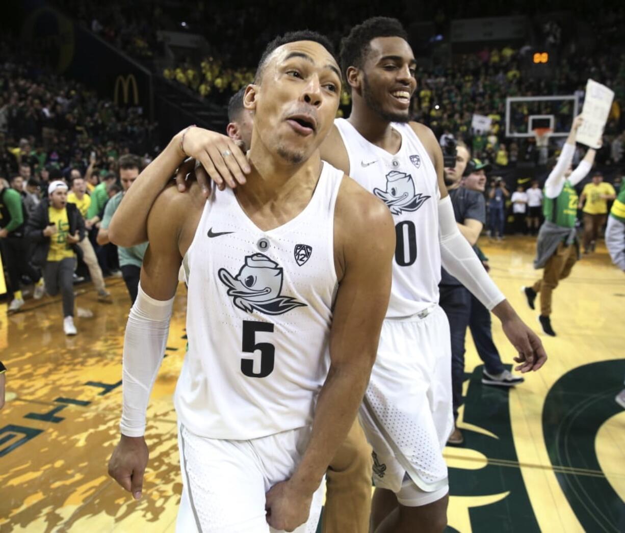 Oregon’s Elijah Brown, left, and Troy Brown Jr. celebrate after Oregon defeated Arizona 98-93 in overtime, as fans run onto the court after an NCAA college basketball game Saturday, Feb. 24, 2018, in Eugene, Ore.