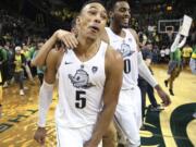 Oregon’s Elijah Brown, left, and Troy Brown Jr. celebrate after Oregon defeated Arizona 98-93 in overtime, as fans run onto the court after an NCAA college basketball game Saturday, Feb. 24, 2018, in Eugene, Ore.