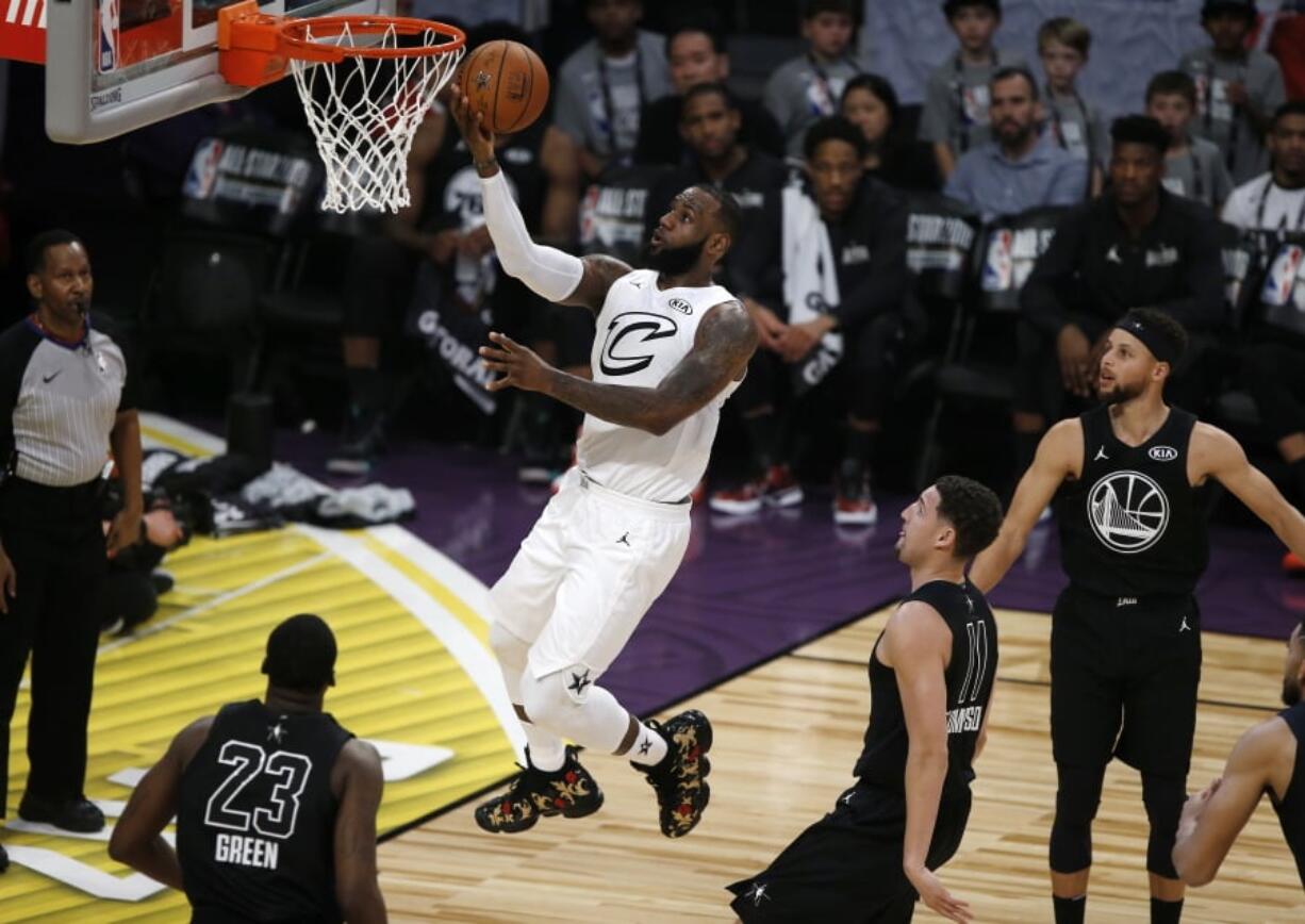 Team LeBron’s LeBron James, second from left, of the Cleveland Cavaliers, shoots as Team Stephen’s Draymond Green, left, of the Golden State Warriors, Klay Thompson, second from right, of the Golden State Warriors, and Stephen Curry, of the Golden State Warriors, defend during the first half of an NBA All-Star basketball game, Sunday, Feb. 18, 2018, in Los Angeles.