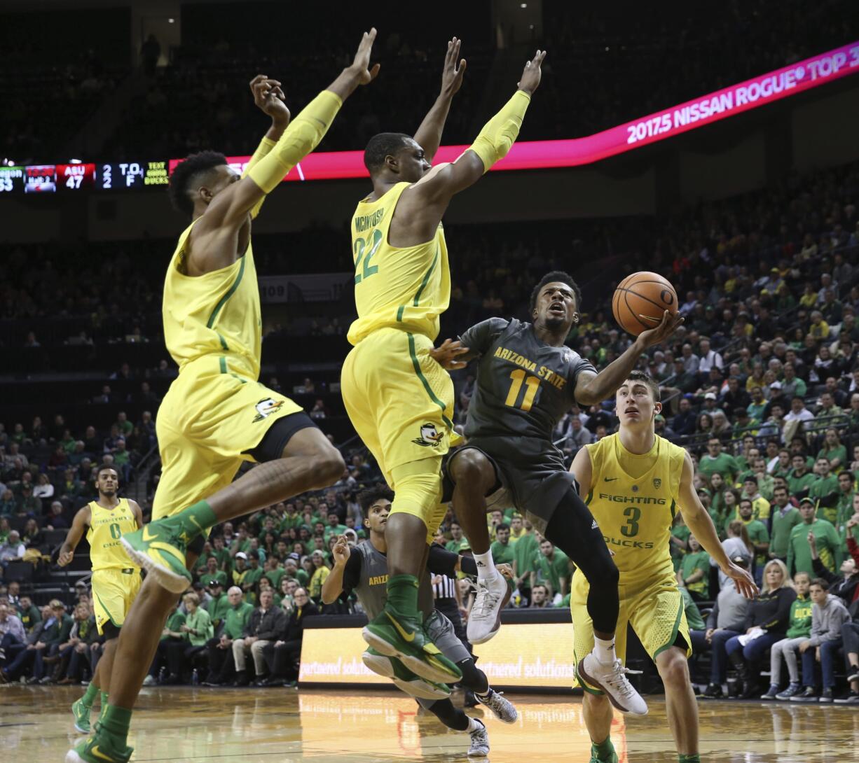 Arizona State's Shannon Evans II, center, shots under pressure from Oregon's Kenny Wooten, left, MiKyle McIntosh and Payton Pritchard, right, during the second half of an NCAA college basketball game Thursday Feb. 22, 2018, in Eugene, Ore.