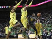 Arizona State's Shannon Evans II, center, shots under pressure from Oregon's Kenny Wooten, left, MiKyle McIntosh and Payton Pritchard, right, during the second half of an NCAA college basketball game Thursday Feb. 22, 2018, in Eugene, Ore.