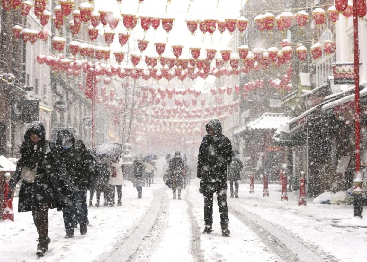 People walk through Chinatown in London, Wednesday Feb. 28, 2018. Britain, which is buffered by the Atlantic Ocean and tends to have temperate winters, saw heavy snow in some areas that disrupted road, rail and air travel and forced hundreds of schools to close.