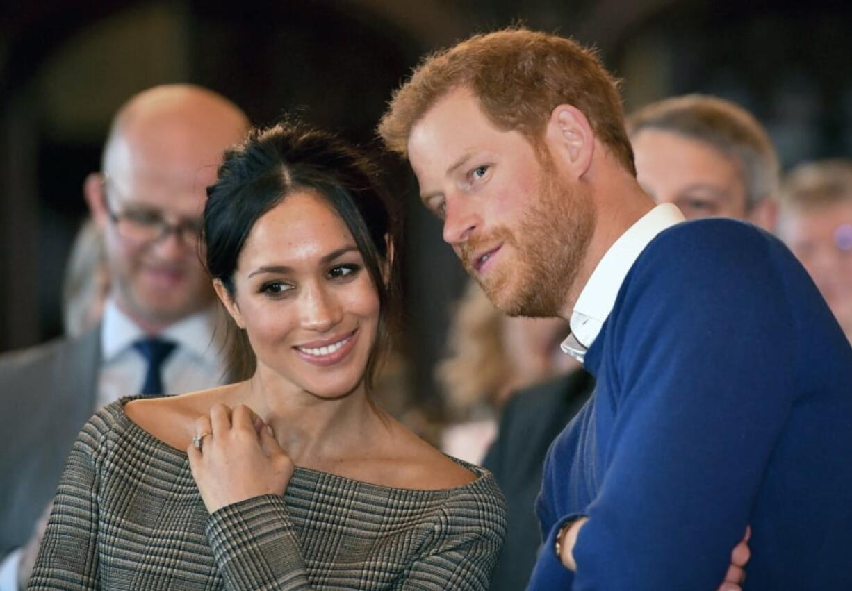 Britain’s Prince Harry talks to Meghan Markle Jan. 18 as they watch a dance performance by Jukebox Collective during a visit to Cardiff Castle, Wales. With Prince Harry and Meghan Markle’s May 19 wedding approaching, the fashion and bridal worlds are abuzz with talk of who the bride will pick to design her dress.