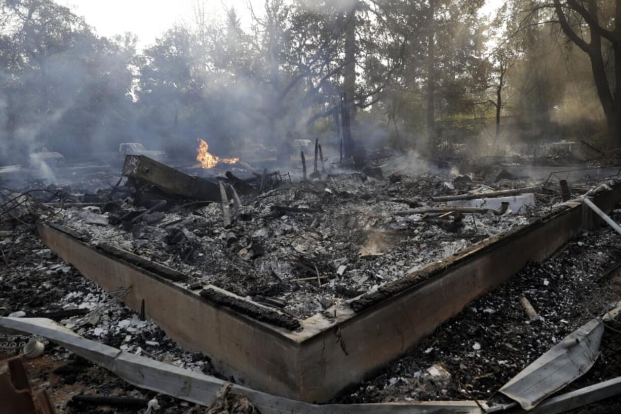 Smoke smolders from a fire-ravaged home destroyed by a wildfire in Sonoma, Calif.