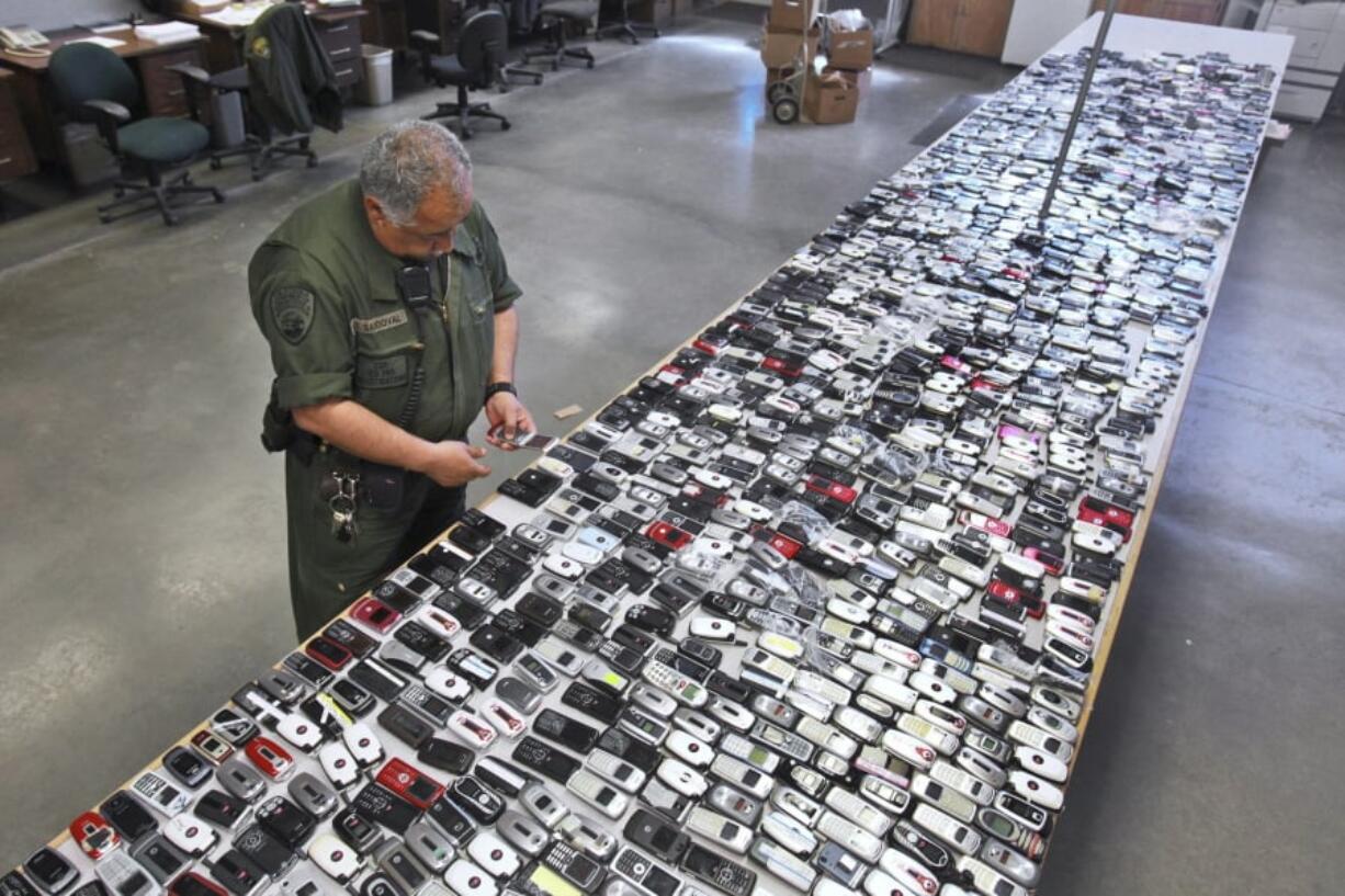 Correctional Officer Jose Sandoval inspects one of the more than 2,000 cell phones confiscated from inmates at California State Prison, Solano in Vacaville, Calif. As prison officials combat contraband cellphones in the hands of the nation’s inmates, a wireless trade group says court orders should be required to shut down the devices.