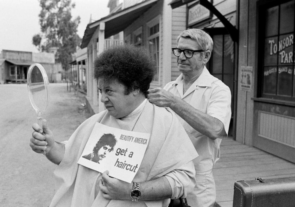 In this Aug. 15, 1968, file photo, comedian Marty Allen, fuzzy-haired member of the comedy team of Allen & Rossi, has his hair styled by barber Sol Goldstein in Hollywood, Calif. Allen’s spokeswoman Candi Cazau said he died Monday of complications from pneumonia. His wife and performing partner Karon Kate Blackwell was by his side. He was 95.