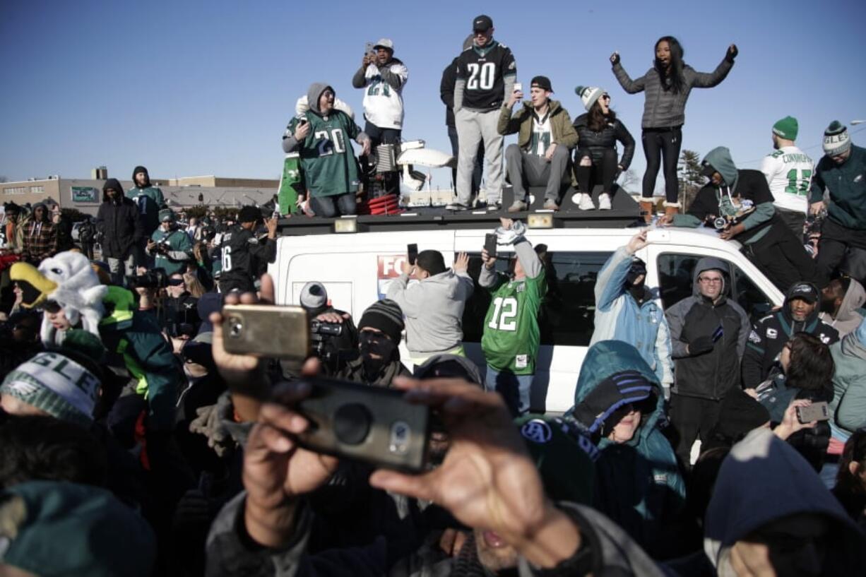 Philadelphia Eagles stand atop a news van while waiting for the team to deplane Monday at Philadelphia International Airport a day after defeating the New England Patriots in Super Bowl 52.