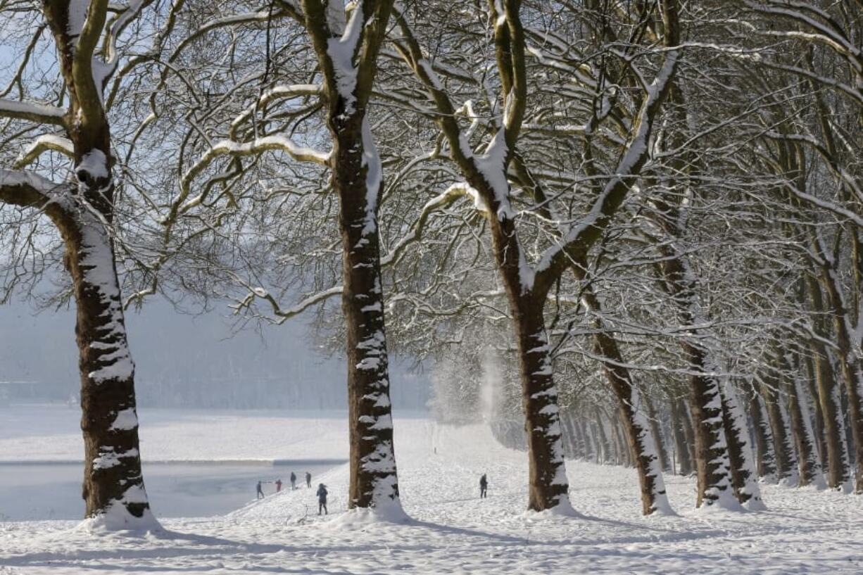 People stroll in the snow-covered park of the Chateau de Versailles, west of Paris, on Thursday.