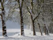 People stroll in the snow-covered park of the Chateau de Versailles, west of Paris, on Thursday.