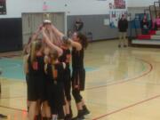 The Washougal girls basketball team hoist the third-place trophy at district after beating Woodland 52-36 (Tim Martinez/The Columbian)